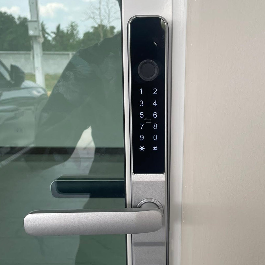Close view of the silver smart door lock keypad and lever on a framed glass door