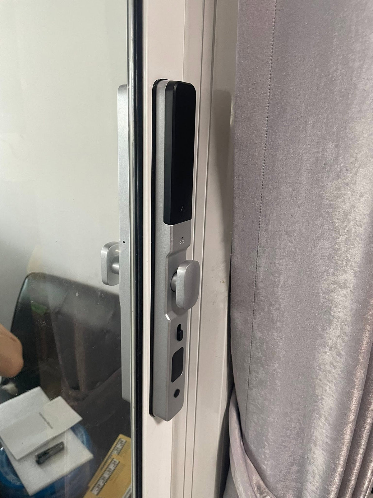 Silver short-handle smart door lock fitted to a white door frame indoors