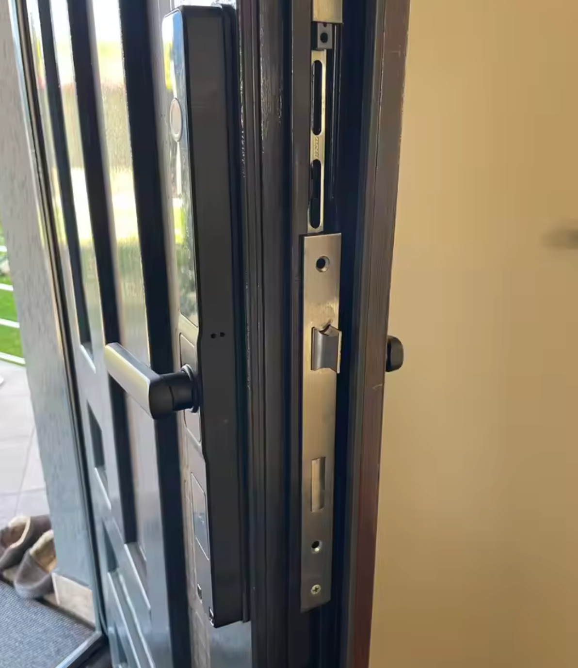 Edge of an open door showing the mortise body and inner handle of the black smart door lock
