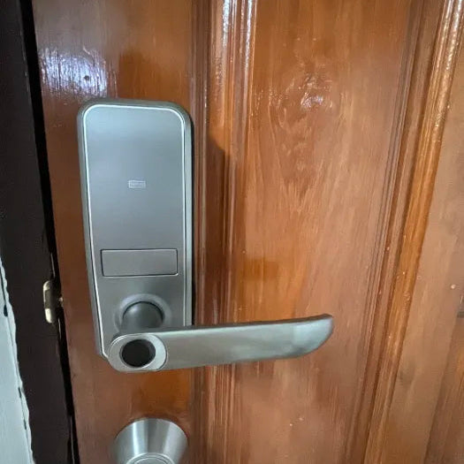 Silver lever-handle smart door lock fitted to a timber door